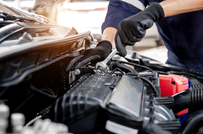 Mechanic servicing car engine using a wrench. Close up.