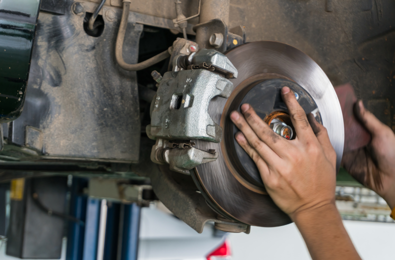 Mechanic using their hands to fix brake disc on vehicle.